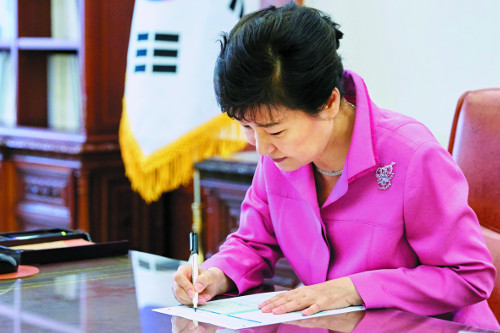 박근혜 대통령이 21일 청와대에서 열린 수석비서관회의를 주재한 뒤 집무실로 돌아와 청년희망펀드 공익신탁 가입신청서에 서명하고 있다. 박 대통령은 일시금 2000만원에다 매달 월급의 20%를 기부하기로 했다.   청와대 제공