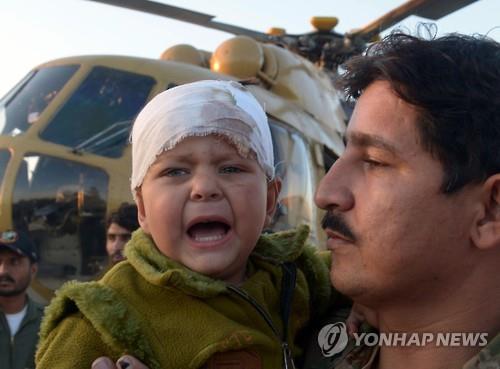 27일 파키스탄 페샤와르 군기지에서 군인이 지진 피해에서 다친 어린이를 옮기고 있다.(AFP=연합뉴스)