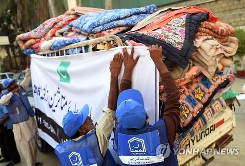27일 파키스탄 남부 카라치에서 자마트-에-이슬라미 당원들이 담요 등 지진 구호품을 트럭에 싣고 있다.(AFP=연합뉴스)