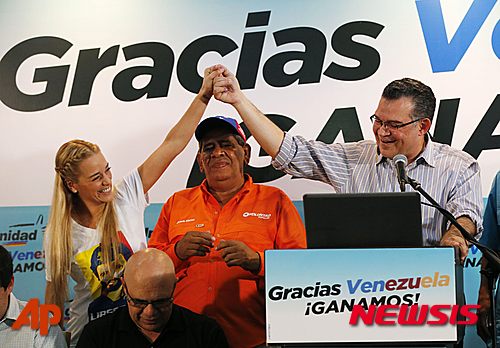 Lilian Tintori, wife of jailed opposition leader Leopoldo Lopez, left, holds hands up with reelected opposition lawmaker Enrique Marquez, who represents Zulia state, during a press conference in Caracas, Venezuela, Monday, Dec. 7, 2015. Venezuela