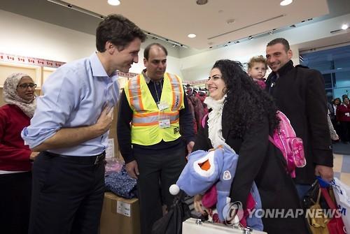쥐스탱 트뤼도 캐나다 총리가 11일(현지시간) 새벽 토론토 국제공항에 도착한 첫 시리아 난민을 맞으며 인사하고 있다.