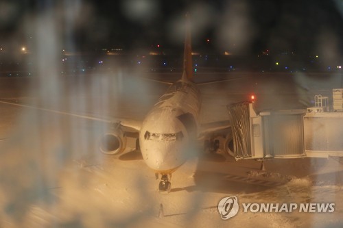 (제주=연합뉴스) 고성식 기자 = 한파가 몰아친 23일 제주공항 활주로에 많은 눈이 쌓이면서 오후 5시 50분부터 운영이 잠정 중단됐다. 이날 운항을 하려던 항공기가 기체에 눈이 쌓인 채 멈춰 서 있다. 2016.1.23     koss@yna.co.kr