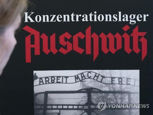 지난 22일(현지시간) 폴란드국립박물관에서 열린 '아우슈비츠' 특별전 입구에서 한 관객이 포스터를 바라보고 있다. (AP=연합뉴스)