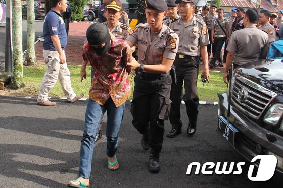 지난 5일 인도네시아 경찰이 14세 소녀 집단성폭행 및 살인 사건 용의자 중 한명을 연행하고 있다. © AFP=뉴스1
