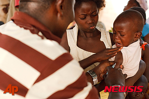 FILE- In this Saturday, Jan. 22, 2011 file photo, a health worker injects a young boy with yellow fever vaccine in Seguela in northern Ivory Coast. On Thursday, May 19, 2016 the UN health agency convened an expert committee to consider whether the epidemic of yellow fever, an acute viral hemorrhagic fever, qualifies as an international public health emergency. (AP Photo/Olivier Asselin, File)