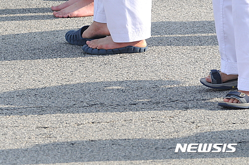 18일 전북도청 앞에서 무주태권도선수권대회 성공을 염원하는 행사가 열린 가운데 퍼포먼스에 참여한 초등학생들이 맨발로 아스팔트 위에 서 있다.