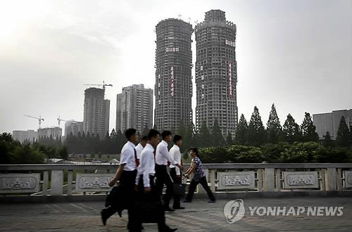 [평양 AP=연합뉴스.자료사진] 지난 6월 27일 평양 려명거리 공사 현장을 주민들이 지나가는 모습