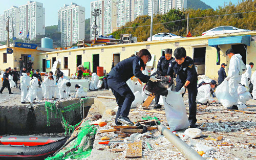 남해해양경비안전본부와 부산해경안전서 소속 직원들이 6일 오후 부산 영도구 중리 해안가에서 제18호 태풍 ‘차바’의 영향으로 유입된 각종 쓰레기를 치우는 정화활동을 펼치고 있다. 남해해경본부는 이날 수중 폐기물 30t을 수거했다. 남해해경본부 제공