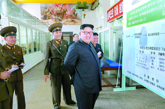북한 김정은이 지난 8월 국방과학원 화학재료연구소를 찾아 '4D탄소/탄소복합재료' 공정을 나열한 설명판 앞에 서 있다. [연합뉴스]