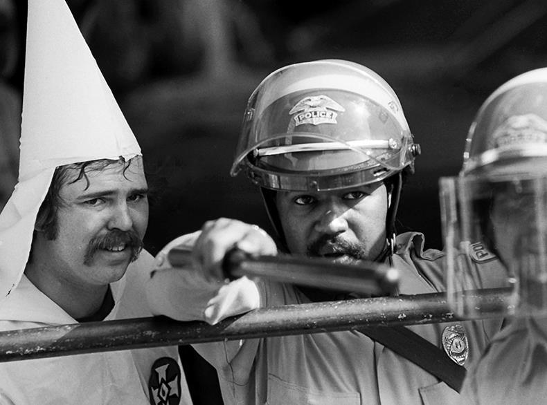 1983 A black policeman protects a KKK member as protesters were closing in on them in at a rally in Austin, Texas.jpg