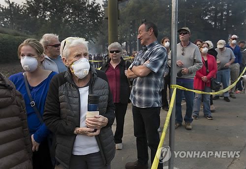 11일(현지시간) 미국 캘리포니아 나파 카운티에서 산불에 대피한 주민들이 피해를 본 주택가를 확인하기 위해 줄지어 서 있는 모습[AP=연합뉴스]