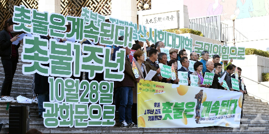 오는 28일 촛불집회 개최 1주년 집회를 앞두고 지난 23일 오후 서울 종로구 세종문화회관 앞에서 열린 ‘촛불 1주년 선포 기자회견’ 참석자들이 손피켓을 들고 구호를 외치고 있다. (사진=황진환 기자)