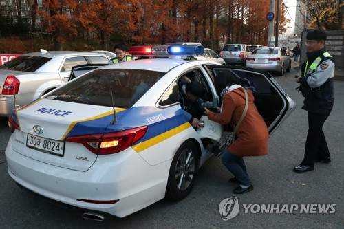'행여나 늦을까봐' (광주=연합뉴스) 정회성 기자 = 2018학년도 대학수학능력시험이 치러진 23일 광주 서구 화정동 광덕고등학교 입구에서 한 수험생이 경찰차를 타고 시험장에 도착하고 있다. 2017.11.23    hs@yna.co.kr