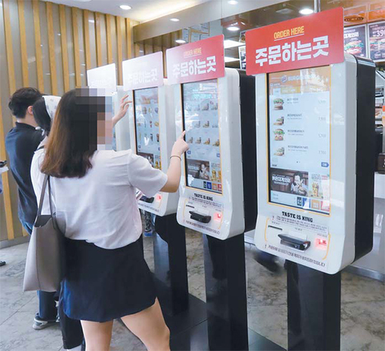 서울의 한 패스트푸드점에서 고객들이 무인 결제 시스템을 이용해 음식을 주문하고 있다. [연합뉴스]
