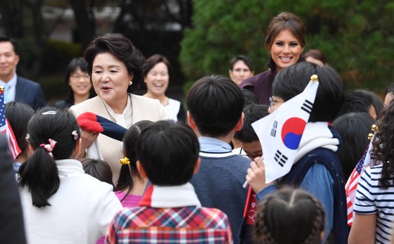 김정숙 여사와 멜라니아 여사가 지난 11월 7일 오후 청와대 녹지원에서 공식환영식에 참가했던 한·미 어린이 환영단에게 감사의 표시로 한국과 미국 국기의 색깔인 흰색, 빨강, 파랑이 들어간 목도리를 선물하고 있다. 청와대사진기자단