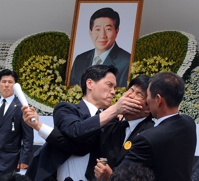 [제46회 스팟뉴스 우수상 사죄하라! 틀어막힌 입] 경복궁 뜰에서 엄수된 고 노무현 전 대통령 영결식에서 이명박 대통령의 헌화, 분향 순서에 민주당 백원우의원이 '사죄하라'고 외치며 뛰어들자 경호팀이 이를 제지하고 있다. 2009. 5.29 한국일보 손용석 기자