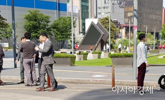 지난 9일 서울 중구 한 차로에서 시민들이 담배를 피우고 있다. 빨간 동그라미 안에는 금연거리 표시가 적혀 있다.