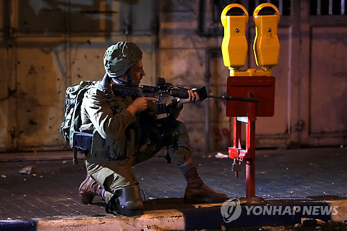 팔레스타인 시위대에 발포하는 이스라엘 군인 (가자지구 EPA=연합뉴스) 이스라엘 주재 미국대사관이 예루살렘으로 이전한 14일(현지시간) 팔레스타인 가자지구에서 대규모 항의시위가 벌어진 가운데, 이스라엘 군인이 돌을 던지는 시위대를 향해 발포 자세를 취하고 있다. 이날 이스라엘군의 발포로 14세 소년을 포함해 팔레스타인 주민이 최소 52명 숨지고 1천200여 명이 다쳤다. lcs@yna.co.kr