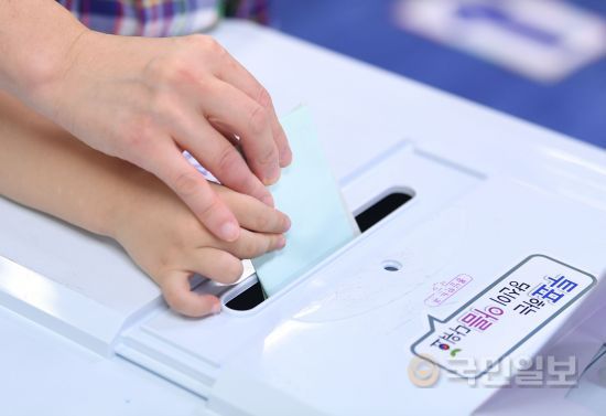 서울 종로구의 한 유권자가 13일 교동초등학교에 마련된 종로 1·2·3·4 가동 제1투표소에서 미래의 유권자가 될 아들과 함께 투표하고 있다. 윤성호 기자