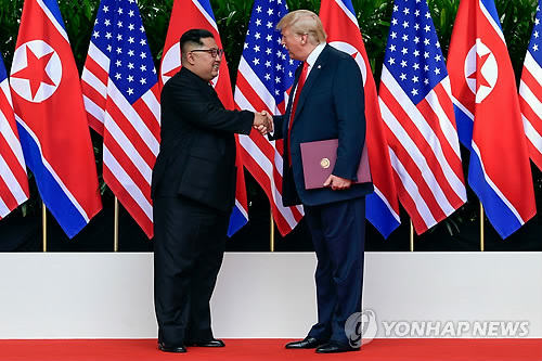서명한 합의문 들고 악수하는 트럼프-김정은 (싱가포르 AFP=연합뉴스) 역사적 첫 북미정상회담이 열린 지난 12일(현지시간) 싱가포르 센토사 섬 카펠라호텔에서 미국 도널드 트럼프 대통령(오른쪽)과 북한 김정은 국무위원장이 서명한 공동합의문을 들고 악수하고 있다. lkm@yna.co.kr