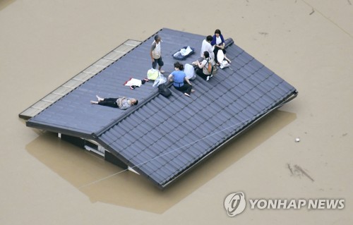 "살려주세요" (오카야마 교도=연합뉴스) 폭우로 물에 잠긴 일본 오카야마(岡山)현 구라시키(倉敷)시 마비초(眞備町) 마을에서 지붕에 대피한 주민들이 구조를 기다리고 있다. 일본 서남부 지역에는 48시간 최고 650㎜에 이르는 폭우가 쏟아졌다. 2018.7.7