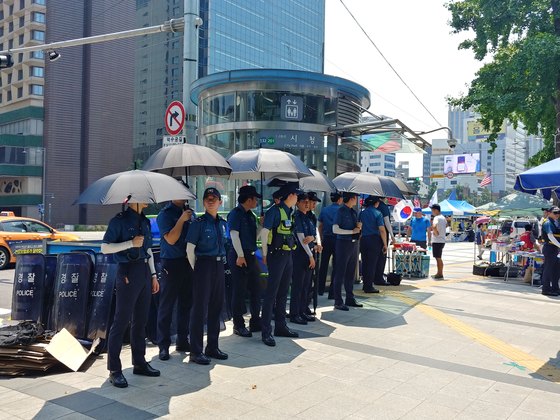 검은 우산과 팔토시로 햇빛을 피하고 있는 의경들. 김정연 기자