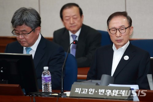 【서울=뉴시스】 사진공동취재단 = 이명박 전 대통령이 첫 재판이 열린 지난 5월23일 서울 서초구 서울중앙지법 417호 대법정 피고인석에 앉아있다. 왼쪽 옆이 강훈 변호사. 2018.05.23. photo@newsis.com