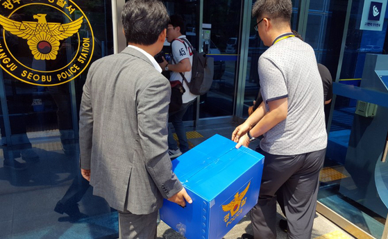 고3 시험지 유출 사건을 수사하는 광주 서부경찰서 소속 수사관이 사건이 발생한 광주 한 고등학교에서 챙겨온 압수품을 옮기고 있다. [연합뉴스]