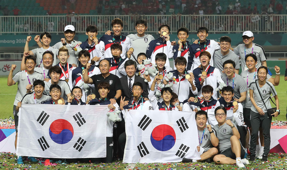 아시안게임 우승 직후 태극기를 펼쳐 들고 함께 포즈를 취한 선수단과 대한축구협회 관계자들. [뉴스1]