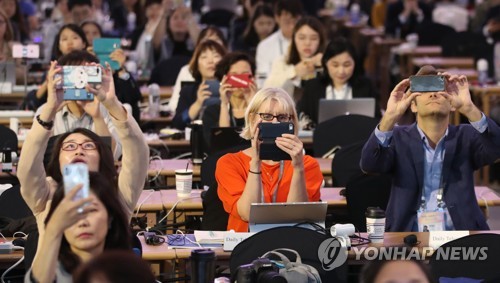 [평양정상회담]'이중요한 순간을 놓칠수없다' (서울=연합뉴스) 서명곤 기자 = 18일 서울 동대문디자인플라자(DDP)에 마련된 남북정상회담 메인프레스센터에서 각국 취재진이  모니터에 표시된 문재인 대통령이 평양 순안공항에 도착해 김정은 북한 국무위원장과 만나는 모습을 휴대전화 카메라에 담고 있다.      seephoto@yna.co.kr  (끝)
