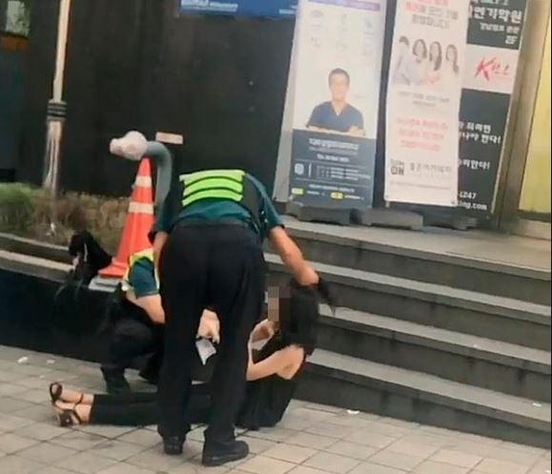 지난 8월 3일 오전 5시30분쯤 서울 강남구 논현동 건물 앞에서 경찰이 만취한 여성의 머리채를 쥐고 흔들고 있다. /조선DB