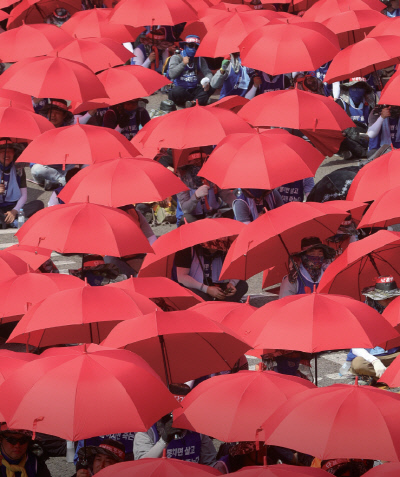 지난 7월 19일 울산 동구 현대중공업에서 전면파업에 들어간 노조원들이 파업 출정식에서 햇볕을 가리기 위해 우산을 쓰고 구호를 외치고 있다. / 연합뉴스