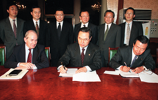 ⓒ연합뉴스 1997년 12월3일 임창열 경제부총리(가운데)와 이경식 한국은행 총재(오른쪽)는 캉드쉬 IMF 총재(왼쪽)가 지켜보는 가운데 IMF 협약서에 서명하고 있다.