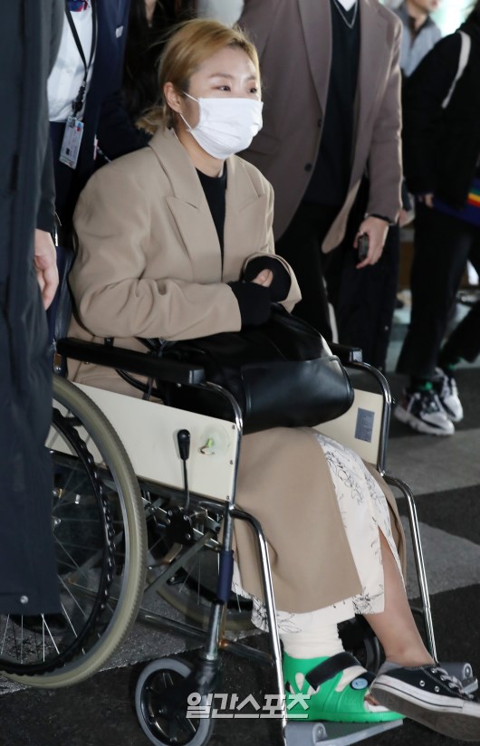 Members of MAMAMOO (Sola, Moonbyeol, Wheein, Hwasa) are leaving the airport, cheered by fans.