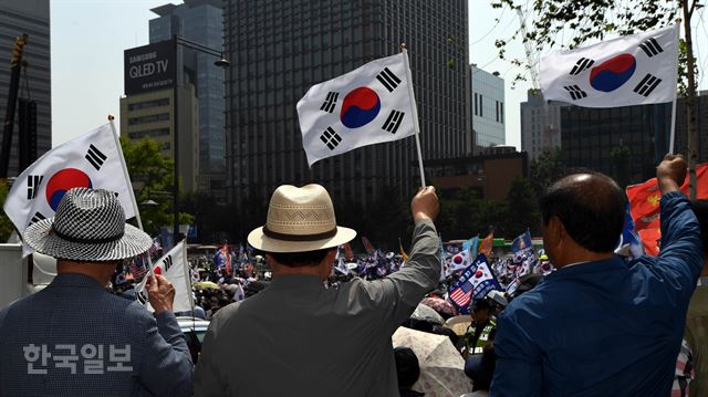 지난해 6월 서울 종로구 교보빌딩 앞에서 열린 '자유민주주의 수호 국민대회'에서 보수단체 회원들이 태극기를 들고 집회에 참가하고 있다. 배우한 기자