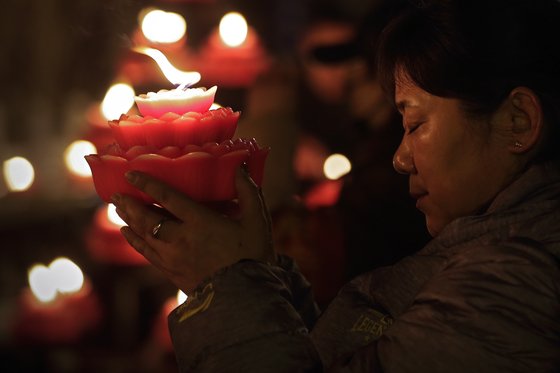 5일(현지시간) 중국 베이징에서 한 여성이 장미모양 초를 들고 기도하고 있다. [AP=연합뉴스]