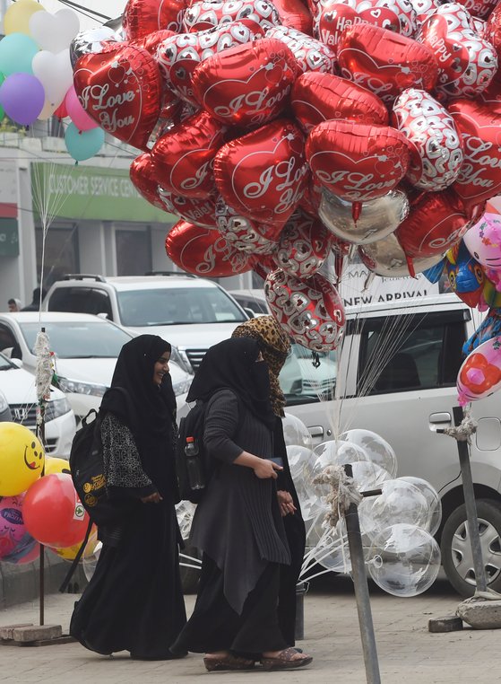 파키스탄 여성들이 13 일 라호르 (Lahore)에서 하트 모양의 발렌타인 데이 (Valentine 's Day) 기념품 앞을 지나고 있다. [AFP=연합뉴스]