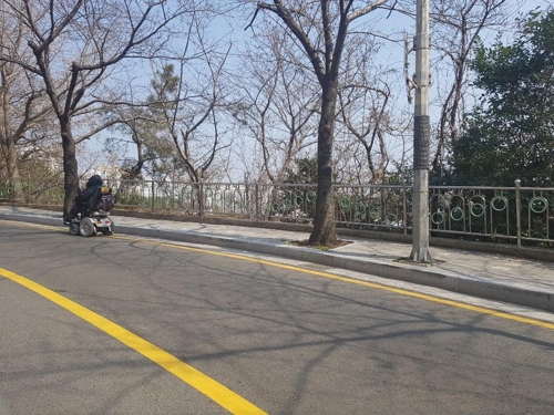 좁은 보행로에 도로로 내몰린 전동휠체어 [차근호 기자]