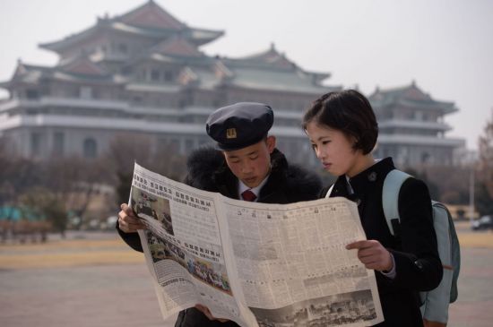 북한 학생들이 27일(현지시간) 평양 거리에서 도널드 트럼프 미국 대통령과 2차 북·미정상회담을 앞둔 김정은 북한 국무위원장의 베트남 하노이 도착 소식을 전하는 노동신문을 펼쳐든 채 읽고 있다. <사진=AFP연합>