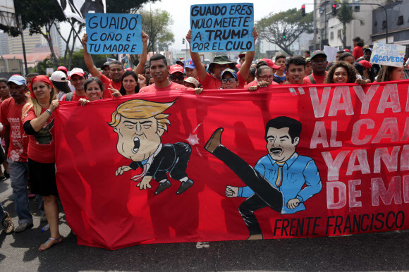 니콜라스 마두로 대통령이 도널드 트럼프 대통령을 걷어차는 모습의 그림을 넣은 현수막을 앞세운 ‘반제국주의 행진’ 참가자들이 30일 수도 카라카스 거리를 행진하고 있다. 카라카스/AFP 연합뉴스