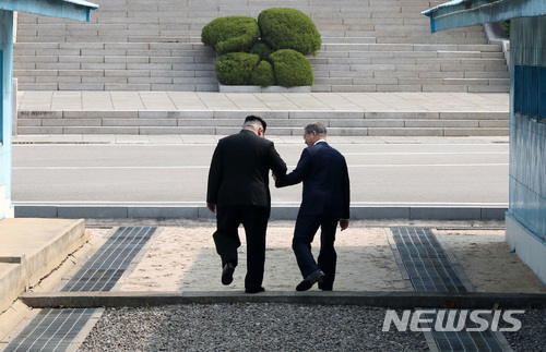 【판문점=뉴시스】전신 기자 = 손을 맞잡은 문재인 대통령과 김정은 국무위원장이  27일 오전 판문점 군사정전위원회 사무실 사이의 군사분계선(MDL)을 넘고 있다. 2018.04.27. photo1006@newsis.com