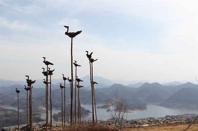 비봉산 정상의 솟대 조형물 뒤로 다도해 같은 풍경이 펼쳐진다.