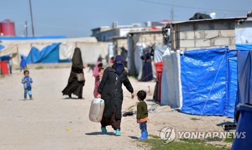 2019년 2월 24일 시리아 북동부의 한 난민 캠프에서 한 여성이 짐을 들고 걷고 있다. [EPA=연합뉴스 자료사진]