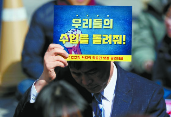 지난 3월 서울 에서 열린 강사 구조조정 반대 집회에서 한 참가자가 피켓을 들고 있다. [연합뉴스]
