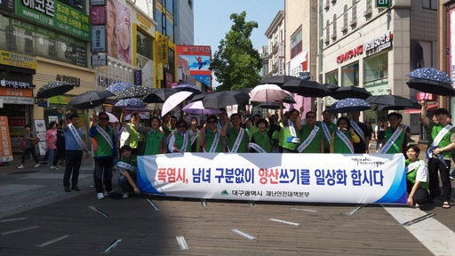 대구시 관계자들이 지난달 동성로에서 양산을 쓴 채 ‘남녀 양산 쓰기’ 운동을 펼치고 있다.