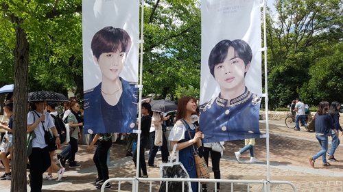 (오사카=연합뉴스) 한 일본인 여성팬이 현수막에 프린트된 BTS 멤버들의 사진을 붙잡고 기념사진을 찍고 있다.