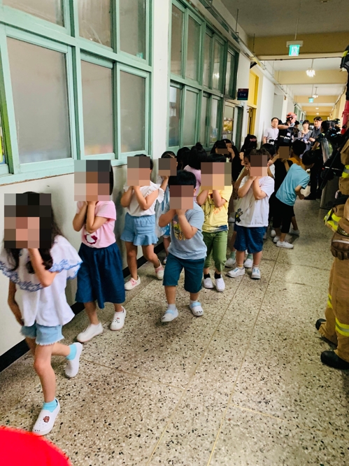 25일 서울 구로구의 한 초등학교에서 학생들이 코와 입을 가린 채 건물 밖으로 대피하고 있다[구로소방서 제공=연합뉴스]