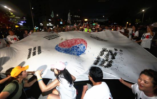 뉴시스. 제74주년 광복절인 15일 오후 서울 종로구 광화문광장에서 '역사왜곡·경제침략·평화위협 아베규탄 및 정의평화실현을 위한 범국민 촛불문화제'를 마친 참가자들이 대형 태극기를 들고 일본대사관 앞으로 행진하고 있다.