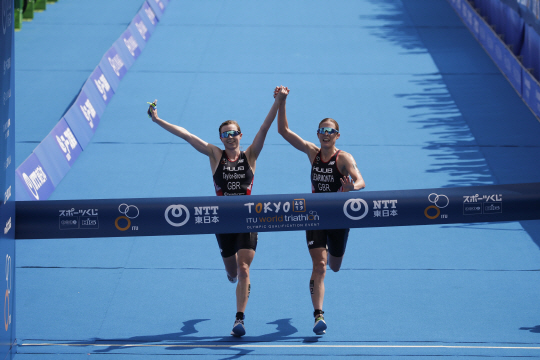 영국의 제시카 리어몬스(오른쪽)와 조지아 테일러브라운(왼쪽)이 15일(한국시간) 일본 도쿄의 오다이바 마린 파크에서 열린 2020 도쿄올림픽 여자 철인3종에서 손을 잡은 채 결승선을 통과하고 있다.  AP연합뉴스