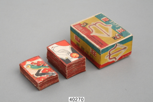 12가지 그림이 그려진 패로 끗수를 겨루는 놀이인 화투. 사진은 ‘활표’ 화투로, 테두리와 뒷면은 붉은색이다. 제품명이 인쇄된 종이 상자에 들어 있으며, 상자의 한쪽 측면에 ‘가짜주의’ 안내문이 인쇄돼 있다. 국립민속박물관 제공